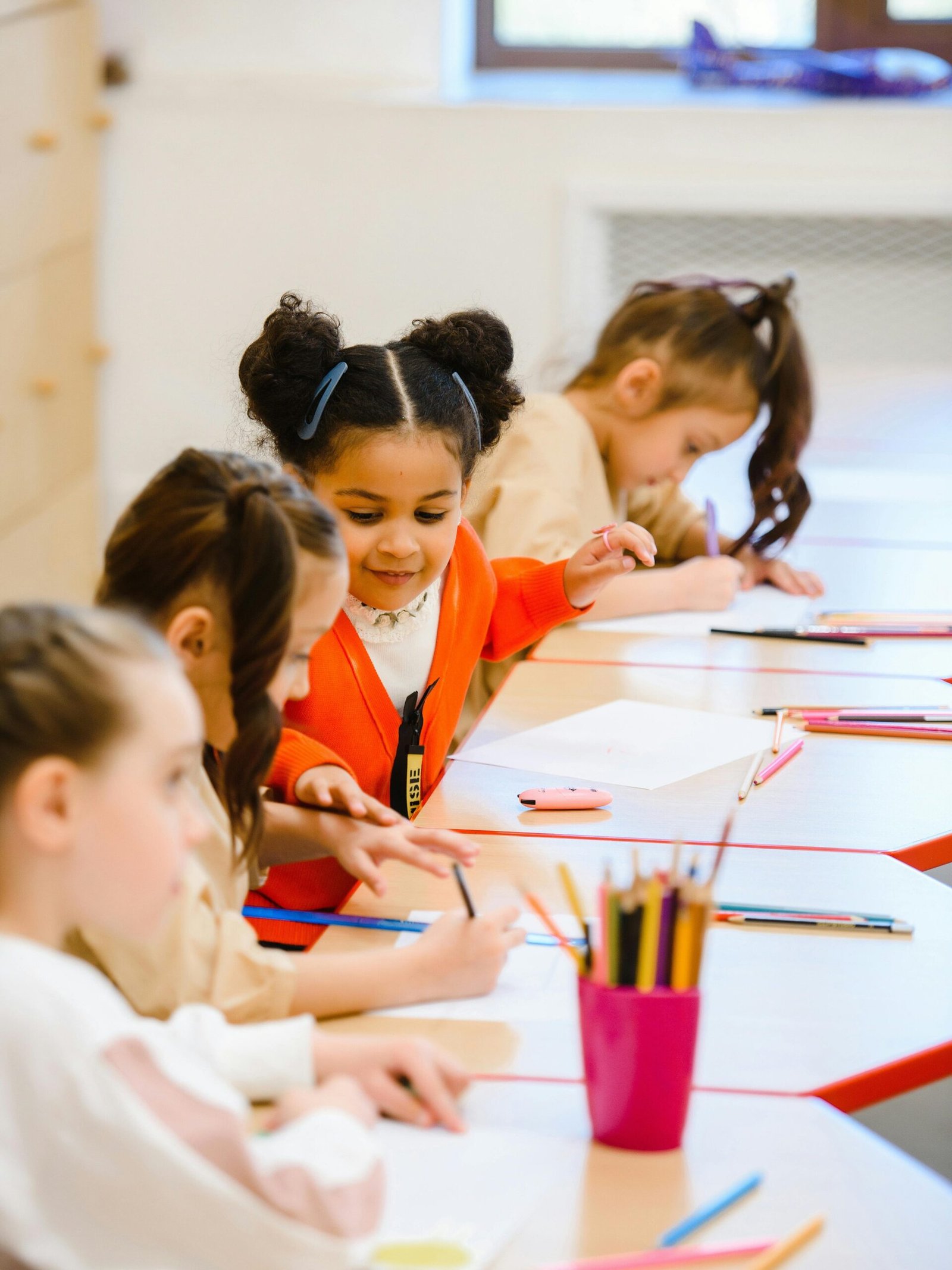 Joyful children drawing and learning in a bright, lively classroom setting.